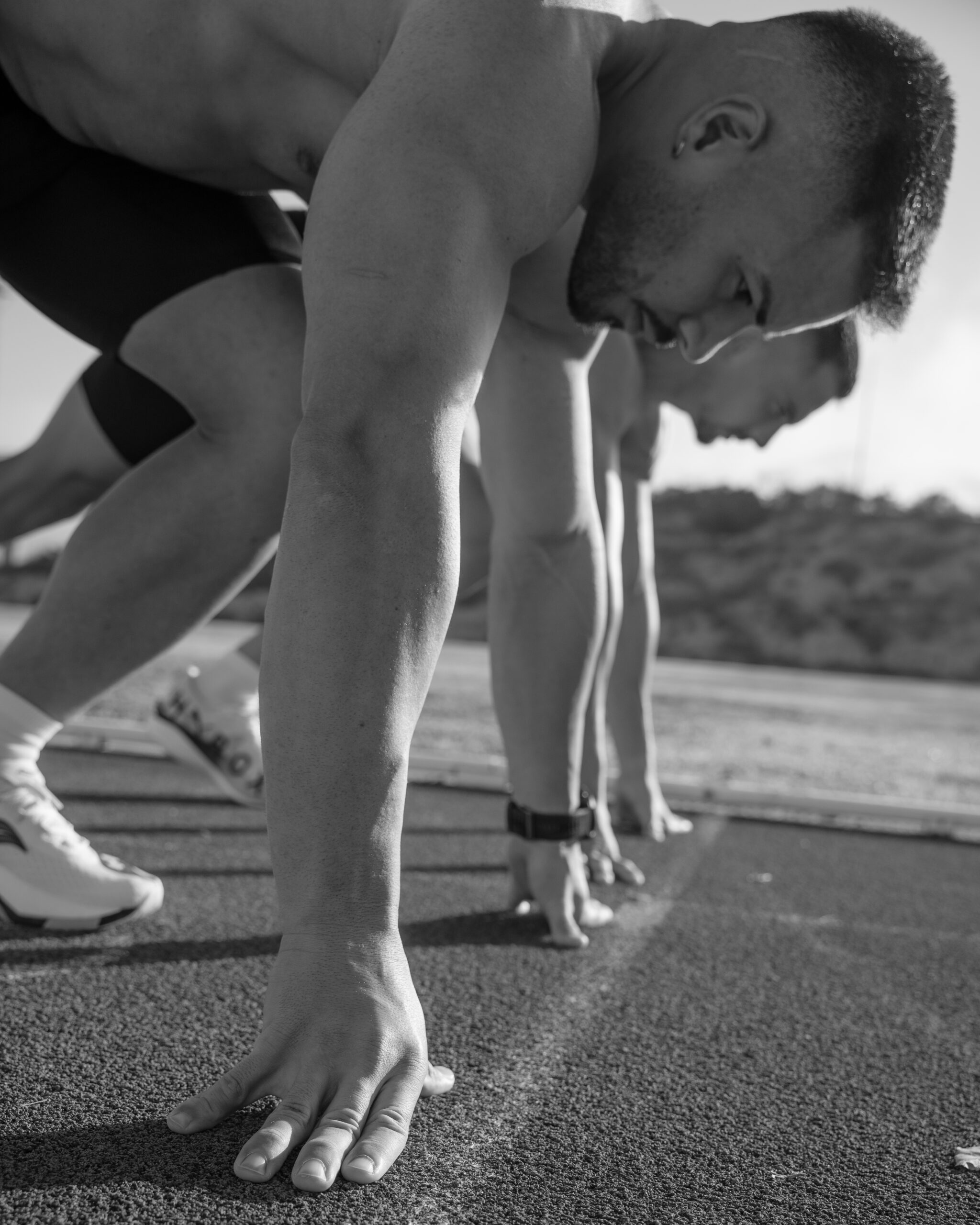 Black and white photo of an athlete bending forward on a running track